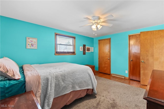 bedroom with baseboard heating, ceiling fan, and wood finished floors