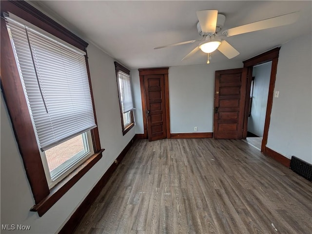 unfurnished room with a wealth of natural light, baseboards, and wood finished floors