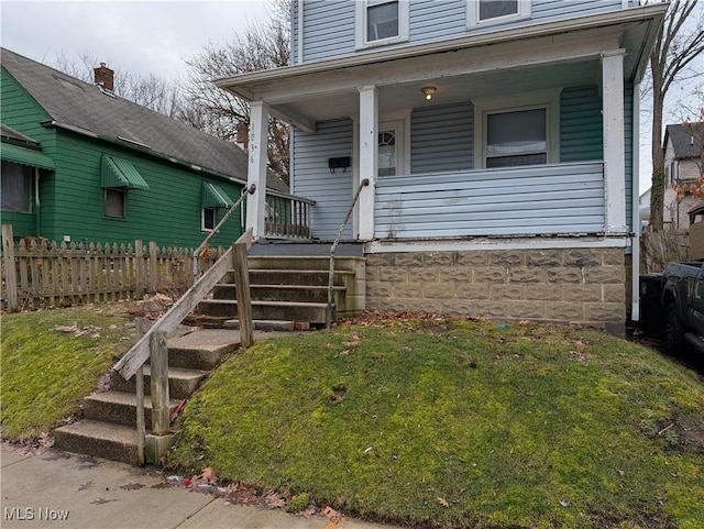 view of front of home featuring a front lawn, stairway, fence, and covered porch