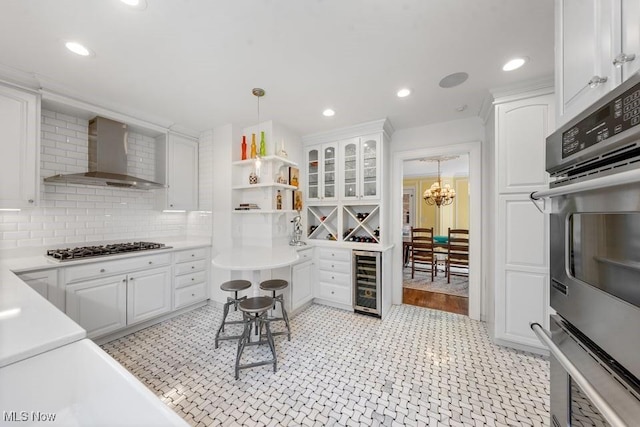 3006 Kingsley Rd, Shaker Heights, OH 44122 - kitchen featuring white cabinetry, stainless steel gas stovetop, beverage cooler, and wall chimney range hood