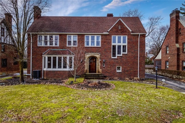 view of front of home with a front lawn, brick siding, and a chimney