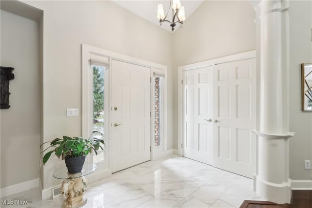 foyer with a chandelier, marble finish floor, and baseboards