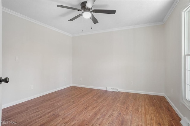 empty room with wood finished floors, visible vents, and ornamental molding