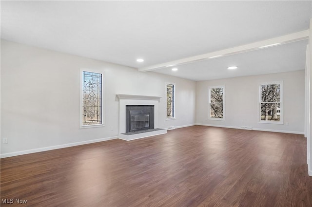 unfurnished living room with a glass covered fireplace, beamed ceiling, dark wood-style floors, and baseboards