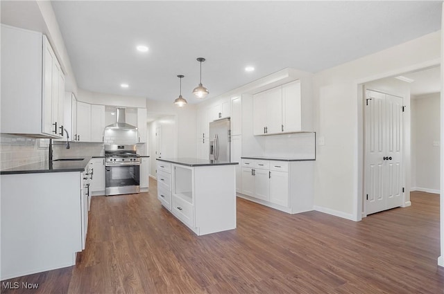 kitchen with a sink, stainless steel appliances, dark wood-type flooring, dark countertops, and wall chimney range hood