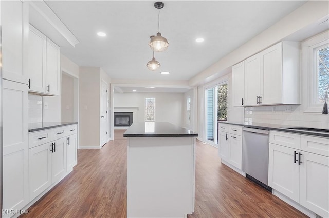 kitchen with dishwasher, dark countertops, and wood finished floors