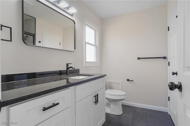 bathroom featuring toilet, vanity, and baseboards