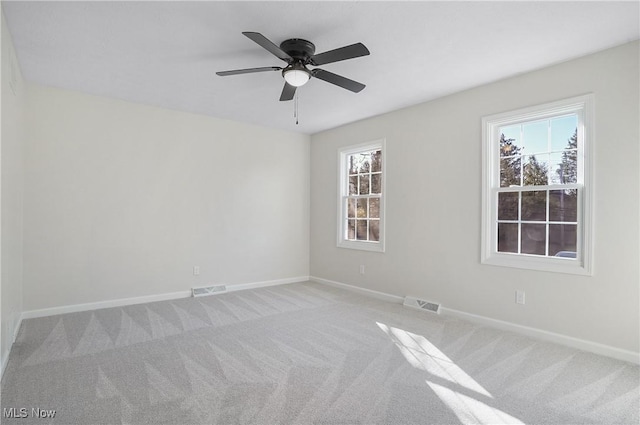 empty room featuring light carpet, visible vents, and baseboards