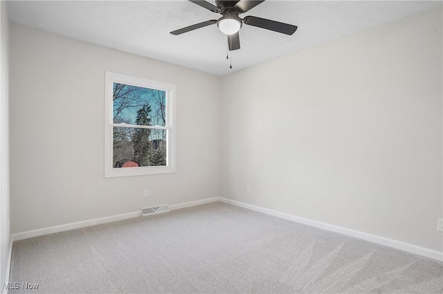 carpeted spare room featuring visible vents, baseboards, and a ceiling fan