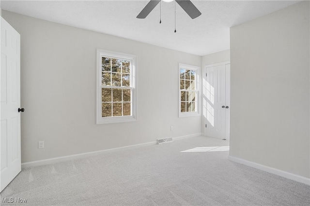 unfurnished room featuring a ceiling fan, baseboards, visible vents, carpet floors, and a textured ceiling