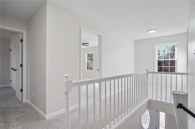 corridor featuring an upstairs landing, baseboards, and carpet floors