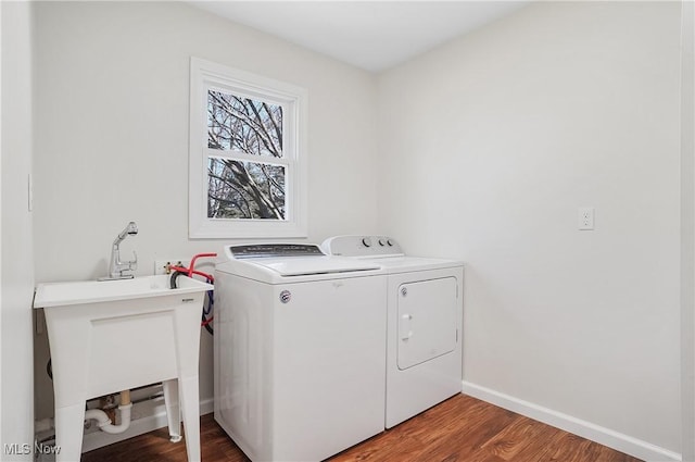 clothes washing area with a sink, wood finished floors, washing machine and dryer, baseboards, and laundry area