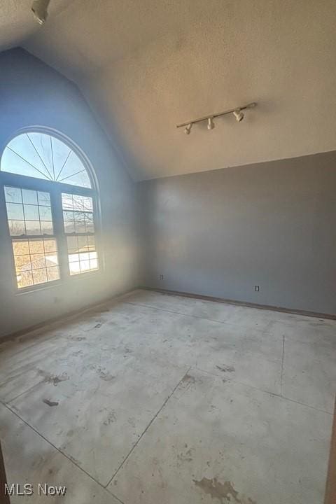 empty room with a textured ceiling and vaulted ceiling