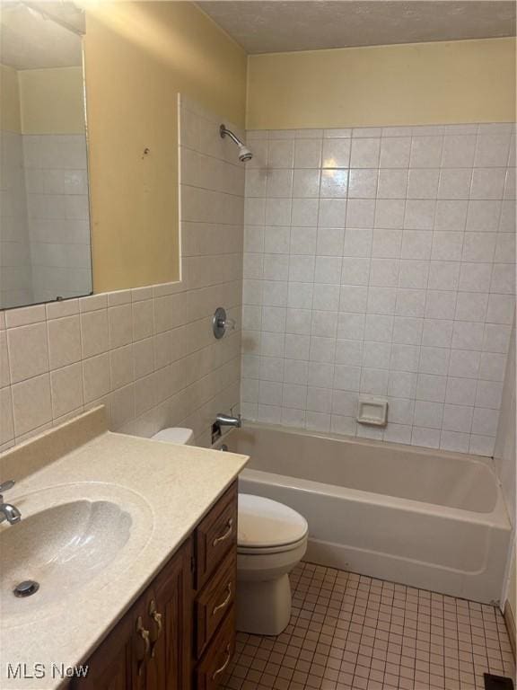 full bathroom with tile patterned floors, toilet, tile walls, washtub / shower combination, and vanity