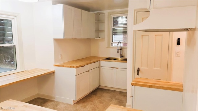 kitchen with a sink, open shelves, butcher block countertops, and white cabinetry