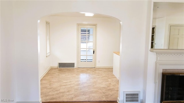 hall featuring arched walkways, visible vents, and baseboards