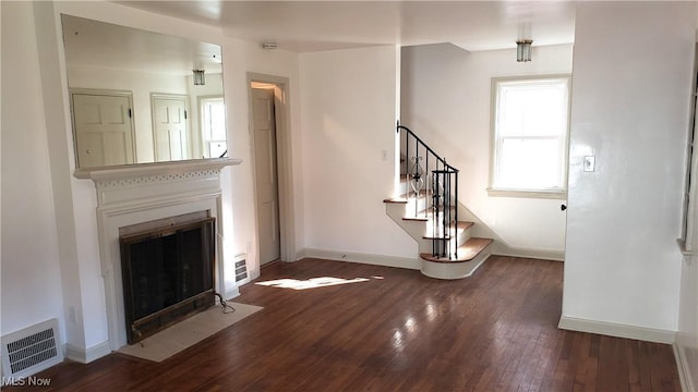 unfurnished living room featuring baseboards, visible vents, a fireplace with flush hearth, stairs, and wood-type flooring