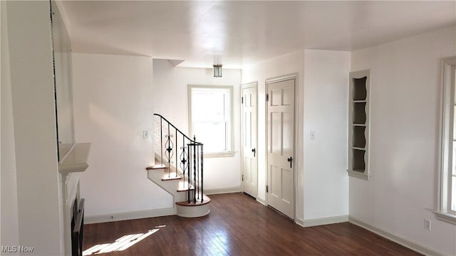 entryway featuring baseboards, dark wood finished floors, and stairs