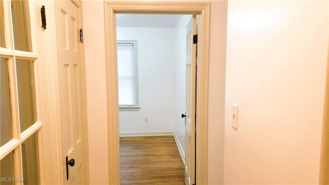 corridor featuring wood finished floors and baseboards