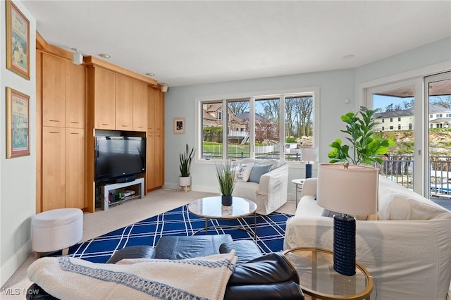 living area featuring light carpet and baseboards