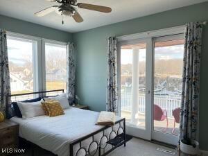 bedroom featuring multiple windows, ceiling fan, and access to outside