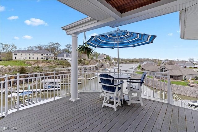 wooden deck featuring outdoor dining area, a residential view, and a water view