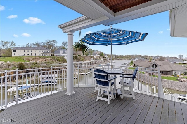wooden deck with outdoor dining space, a residential view, and a water view