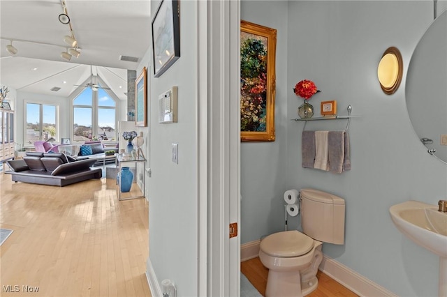 bathroom with a ceiling fan, wood finished floors, baseboards, vaulted ceiling, and toilet