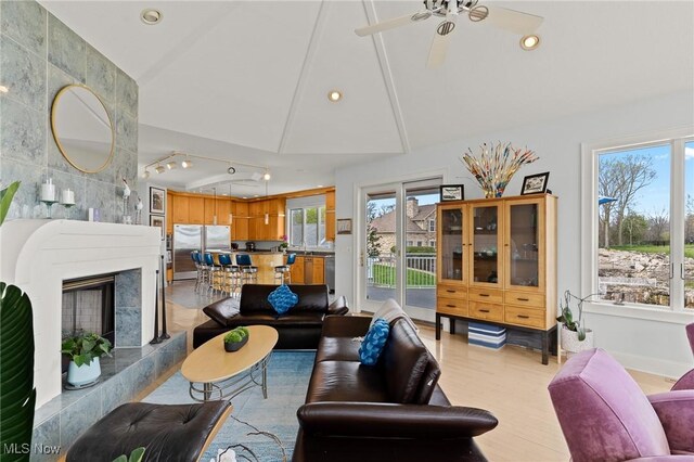 living room with a high end fireplace, light wood finished floors, recessed lighting, and a wealth of natural light