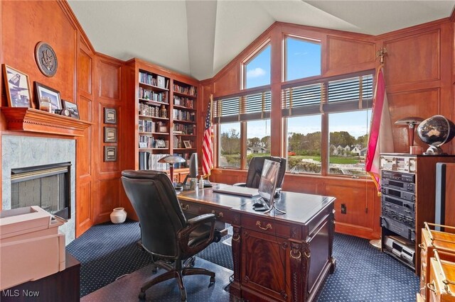 office area with a fireplace, dark colored carpet, and high vaulted ceiling