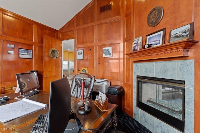 office space featuring visible vents, wood walls, vaulted ceiling, a fireplace, and a decorative wall