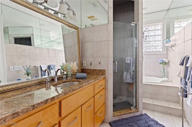 full bathroom featuring tile patterned floors, tile walls, a stall shower, and vanity