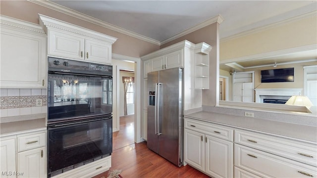 kitchen with ornamental molding, wood finished floors, stainless steel fridge, and dobule oven black