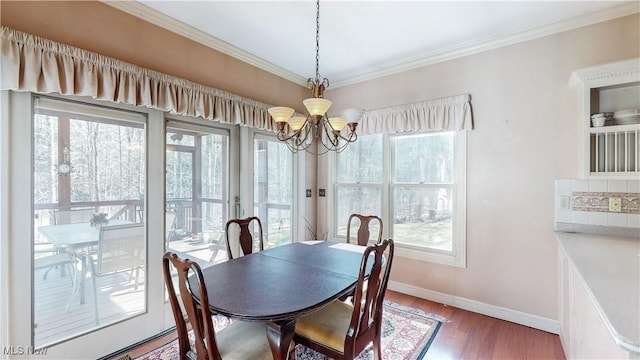 dining space with baseboards, wood finished floors, an inviting chandelier, and ornamental molding