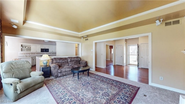 living area with a raised ceiling, baseboards, visible vents, and carpet floors