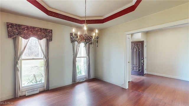 unfurnished room with wood finished floors, baseboards, visible vents, a raised ceiling, and a notable chandelier