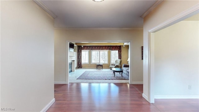 hallway featuring baseboards, wood finished floors, and crown molding