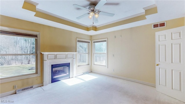 unfurnished living room with a raised ceiling, a fireplace with flush hearth, carpet, and visible vents