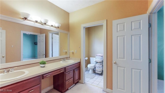 full bathroom with double vanity, tile patterned flooring, toilet, and a sink