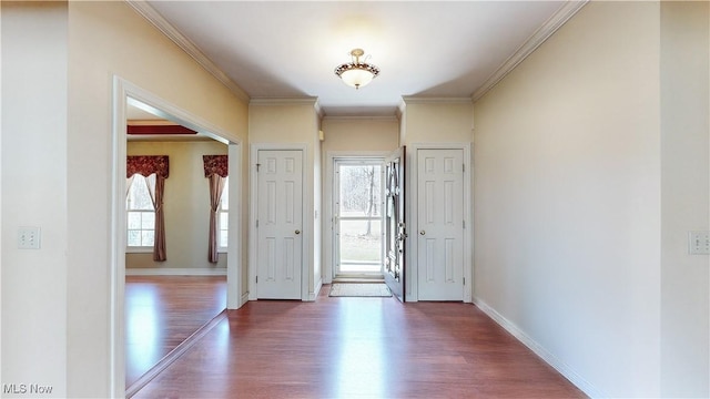 foyer with a wealth of natural light, baseboards, wood finished floors, and crown molding