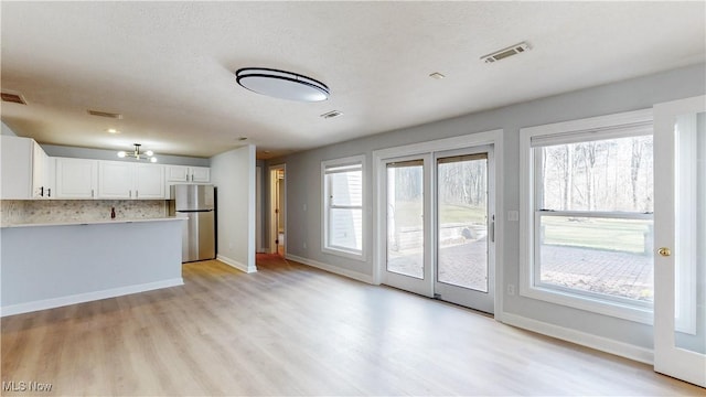 unfurnished living room featuring visible vents, light wood-style floors, and a healthy amount of sunlight