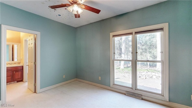 empty room featuring visible vents, ceiling fan, baseboards, light carpet, and a sink