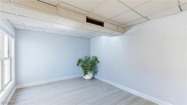 empty room with wood finished floors, baseboards, and a drop ceiling