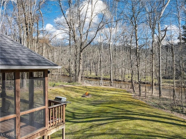 view of yard with a forest view and a sunroom