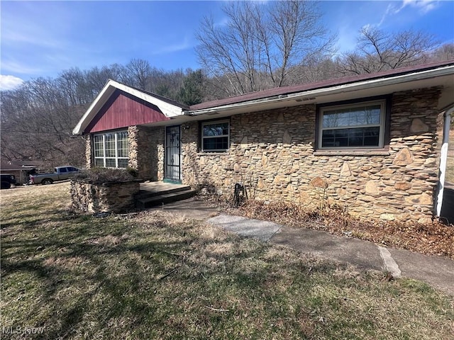 view of front of house with a front yard and stone siding