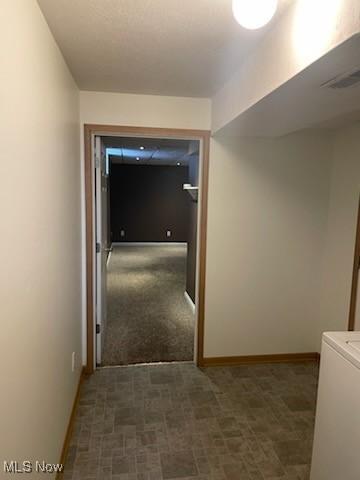 corridor featuring visible vents, washer / dryer, carpet, and baseboards