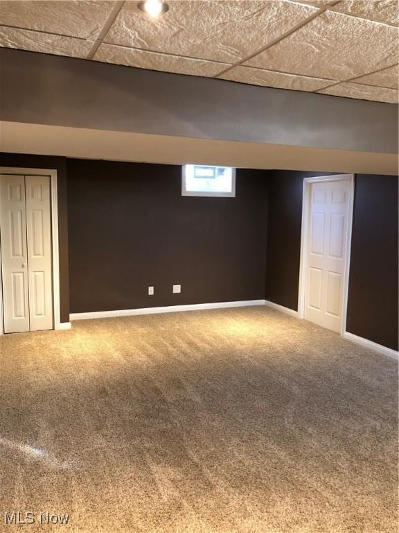 basement with carpet flooring, baseboards, and a drop ceiling