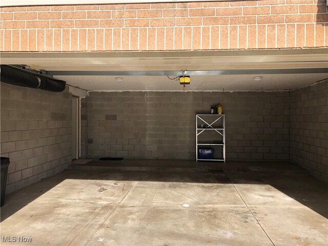 garage featuring concrete block wall and a garage door opener