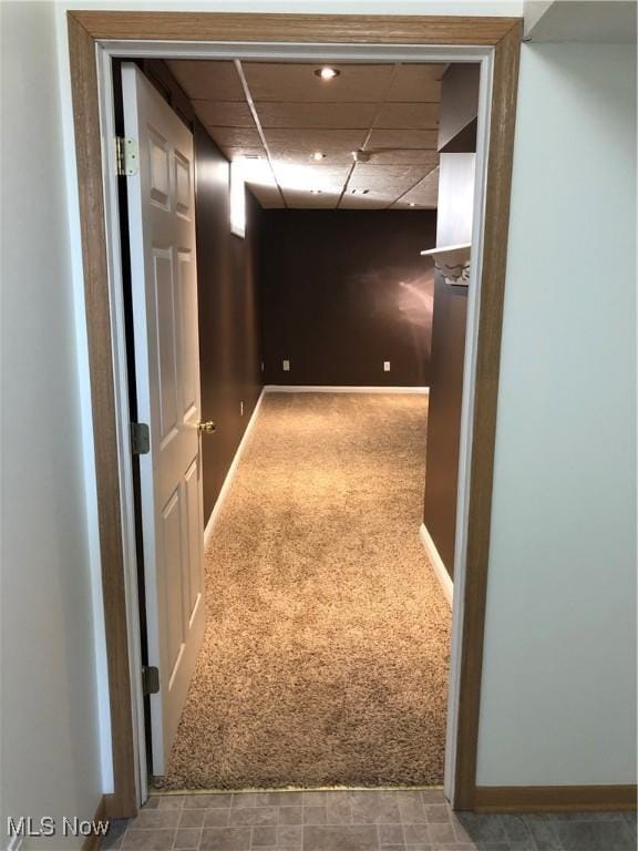 hallway featuring a paneled ceiling, baseboards, and carpet floors