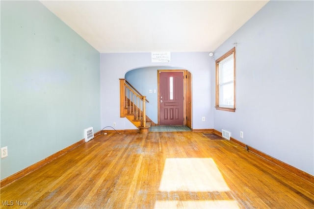 entrance foyer with wood finished floors, stairway, arched walkways, and visible vents